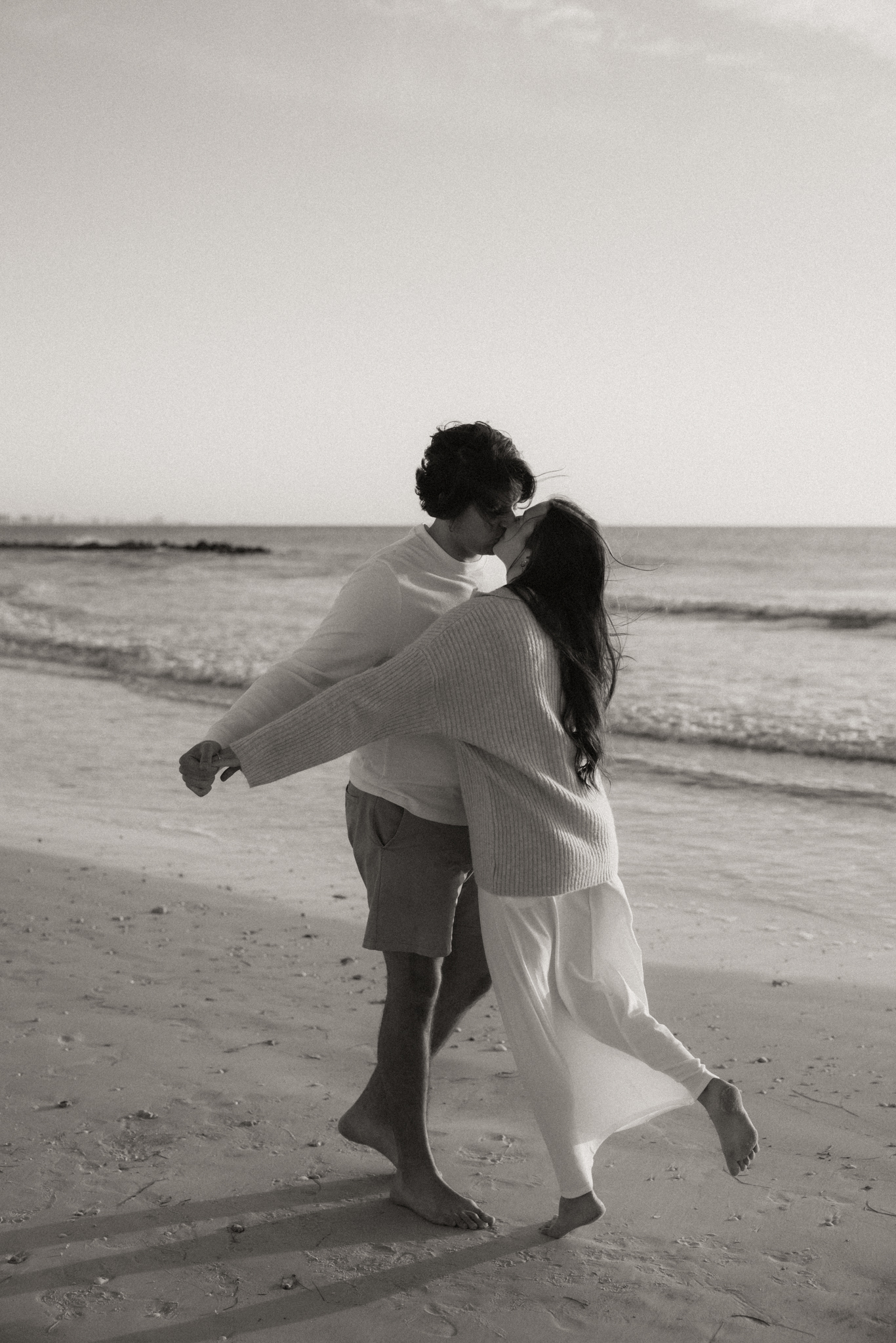 Couple in motion on the beach as they kiss. Black and white.