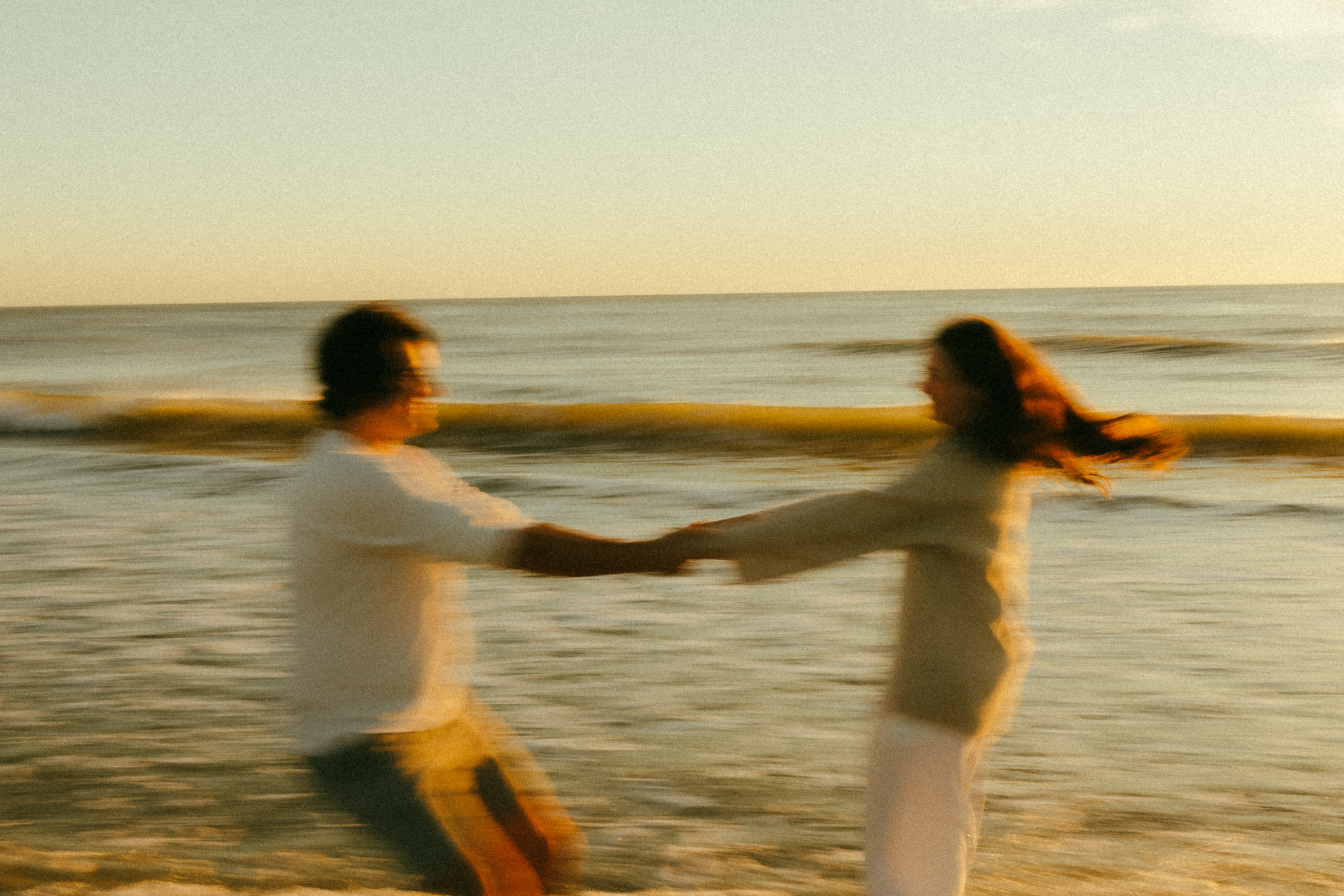 Motion blur photo of couple spinning on a Florida beach. Waves in the background