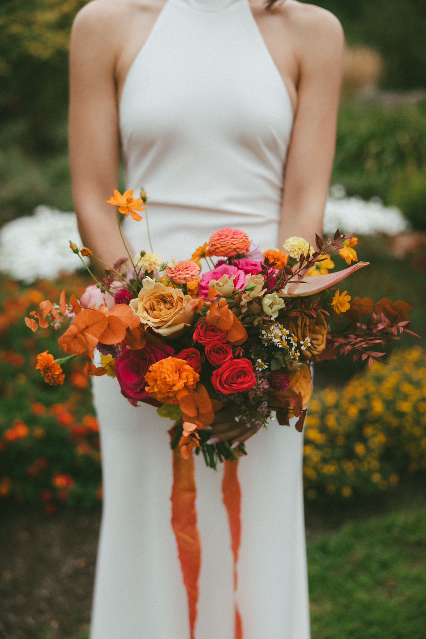 Bride holding bouquet, hot pink, orange, and yellow colors