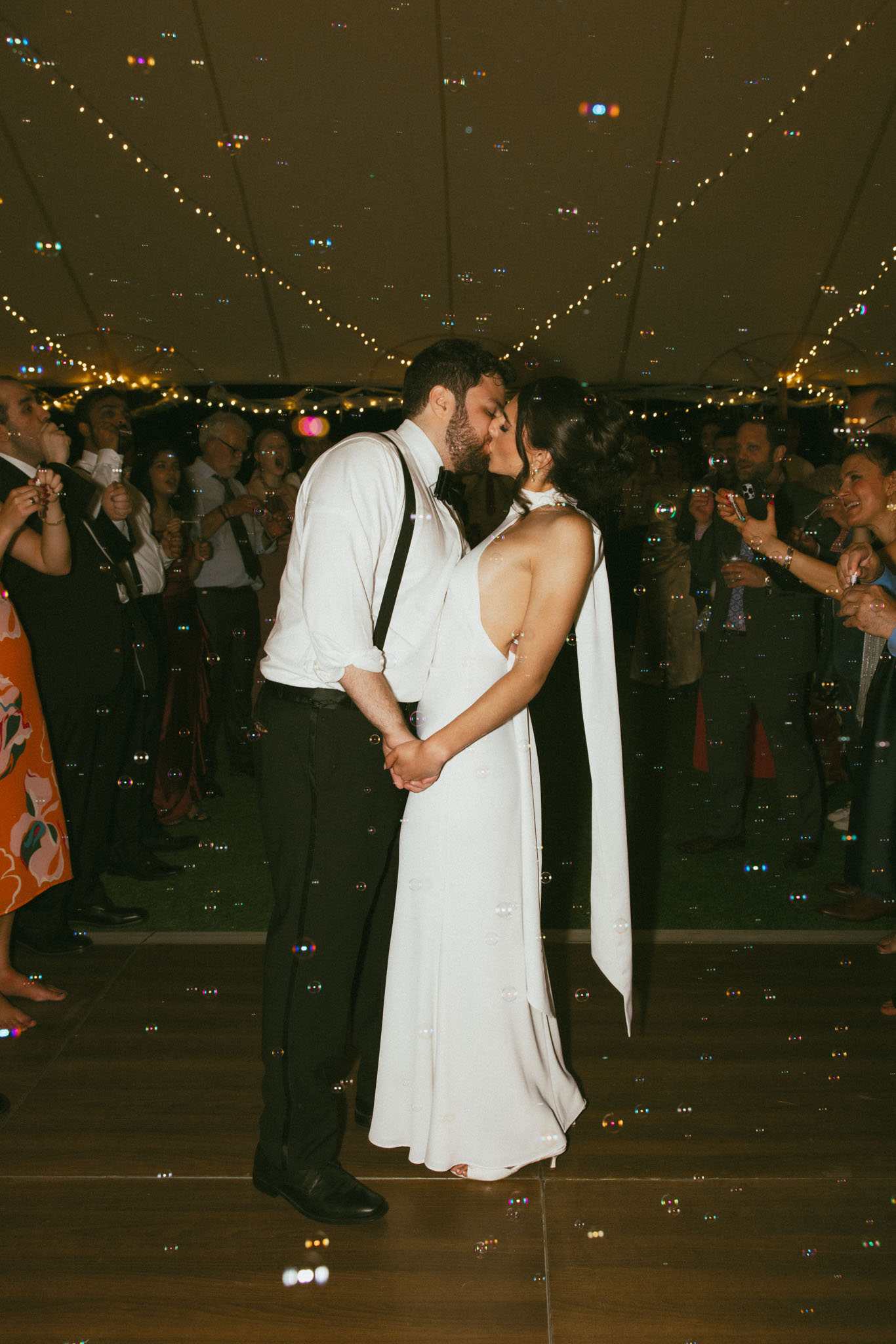 Bride and groom kissing with bubbles floating around them