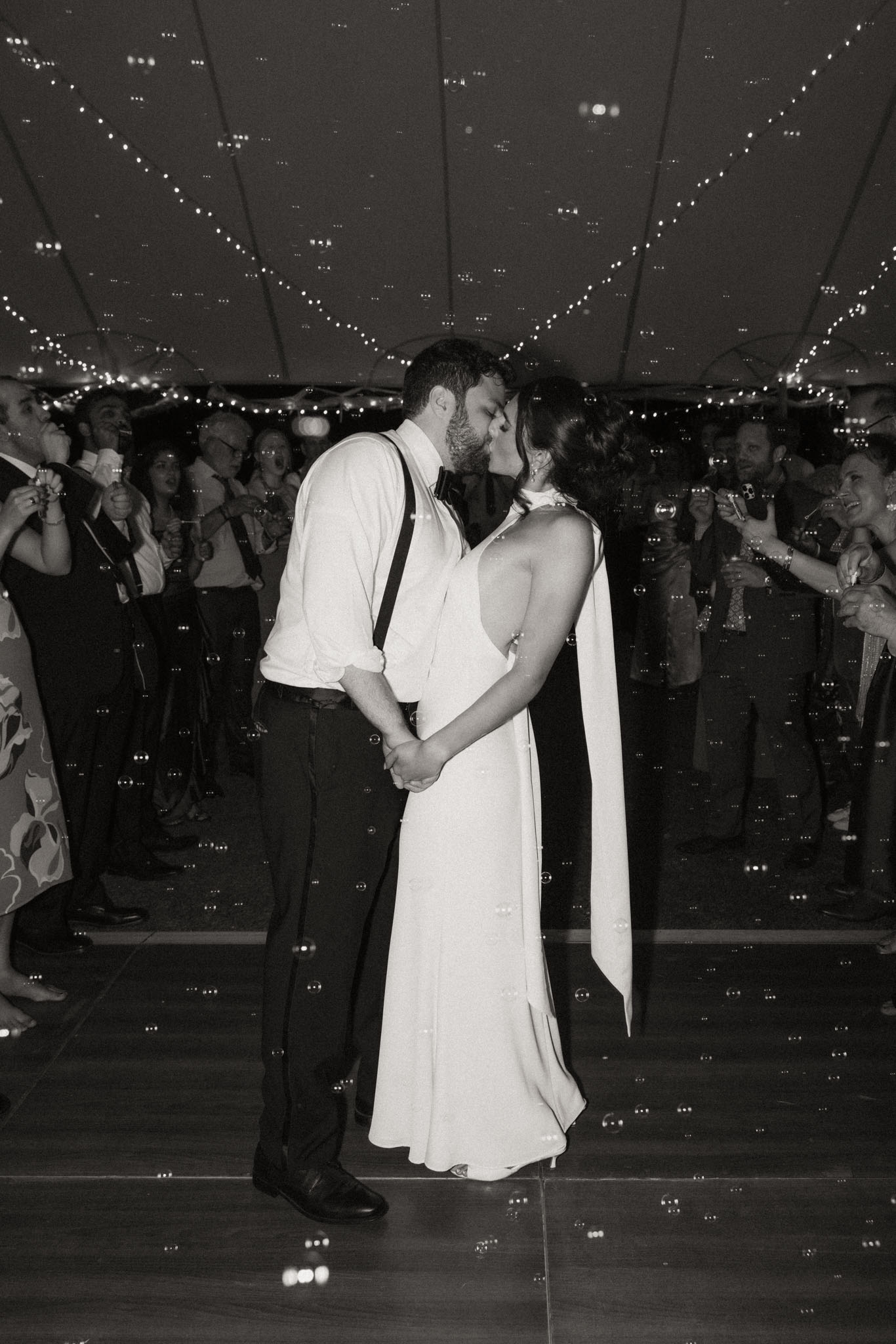 Bride and groom kissing with bubbles floating around them black and white