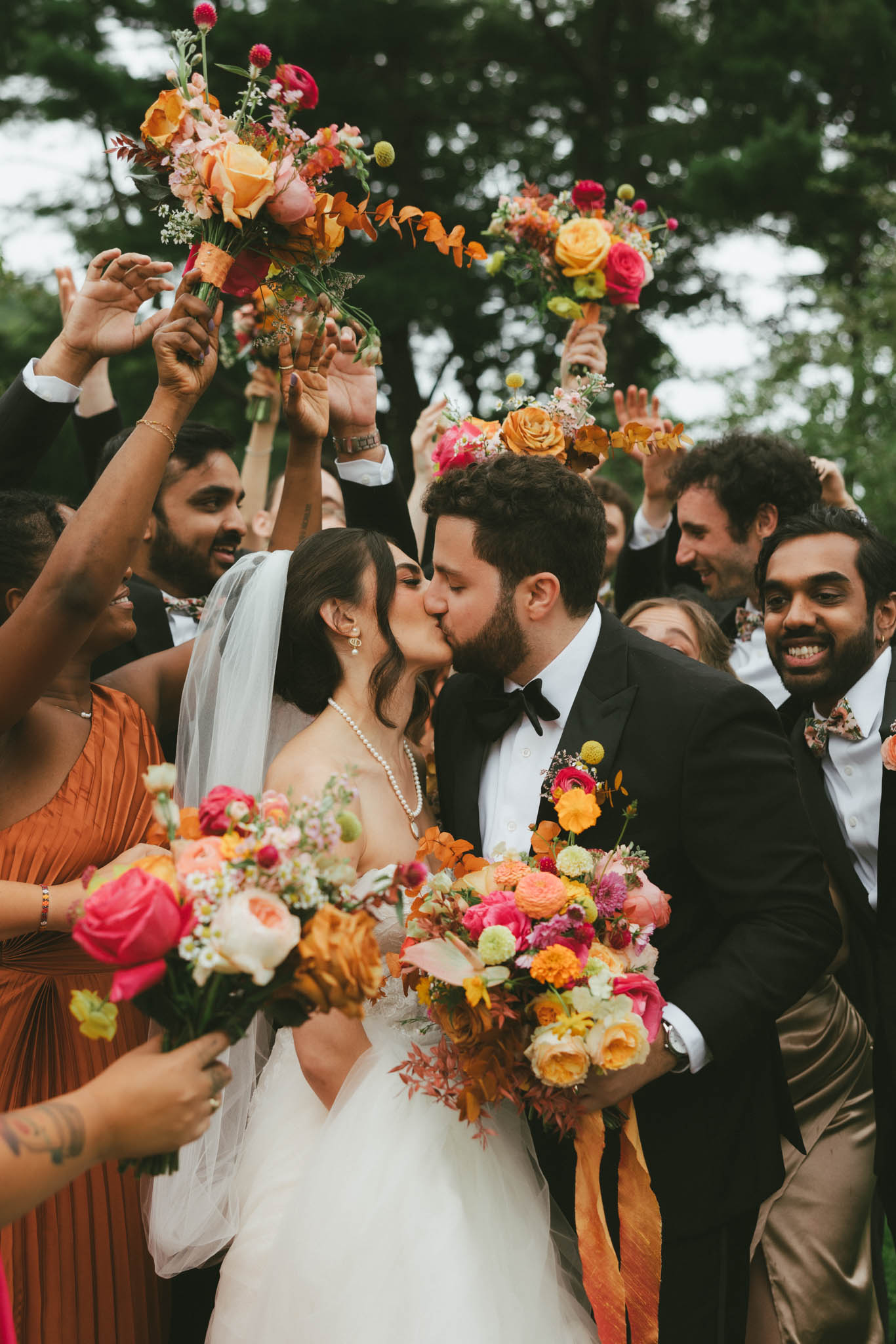 Bride and groom kissing with wedding party cheering. The Gardens at Uncanoonuc Mountain Wedding