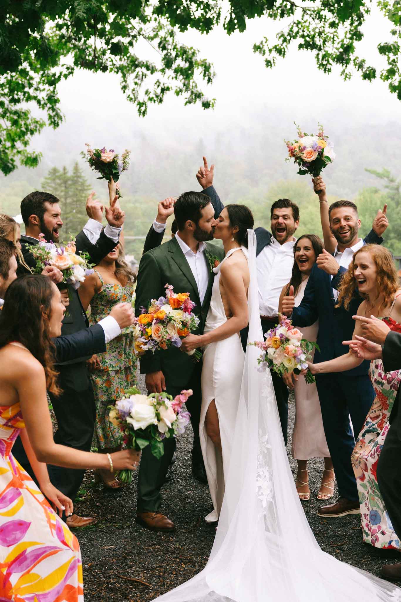 Bride and groom kiss while wedding party cheers at Madbush Falls Wedding in VT.